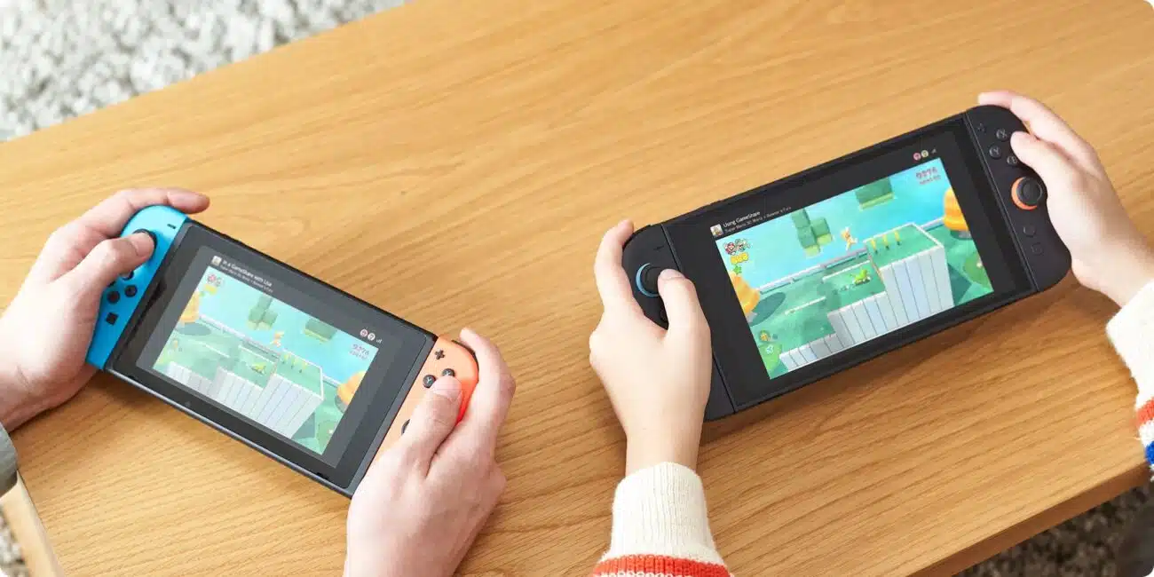 Une Switch 1 dans des mains d'adulte à gauche / une Switch 2 dans des mains d'enfant à droite